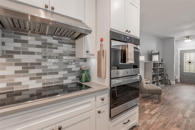 16 Wildwood Lake Dr, Huntsville, TX 77340 - kitchen with under cabinet range hood, stainless steel double oven, tasteful backsplash, black electric cooktop, and white cabinetry