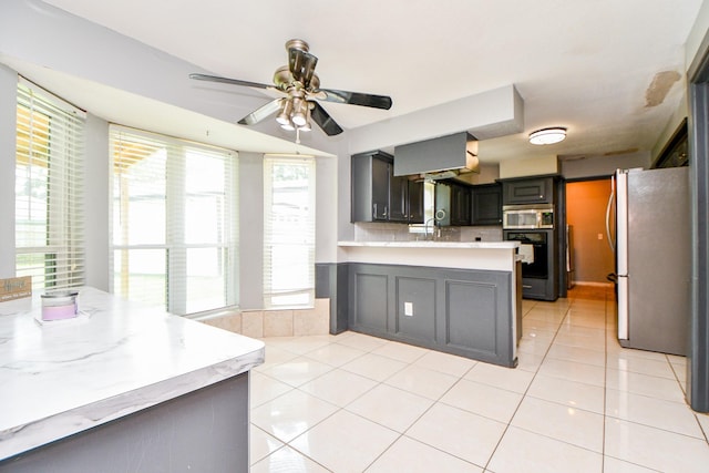 4719 Theall Rd, Houston, TX 77066 - kitchen with stainless steel appliances, a peninsula, light countertops, a ceiling fan, and light tile patterned floors