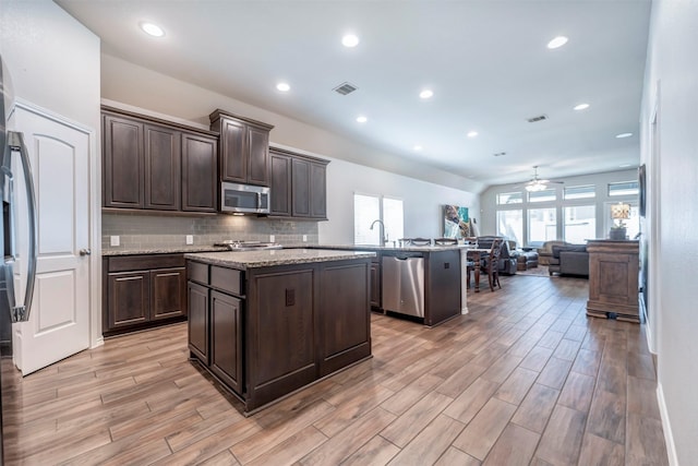 211 Clementine Ct, Montgomery, TX 77316 - kitchen featuring stainless steel appliances, a kitchen island, open floor plan, dark brown cabinetry, and recessed lighting