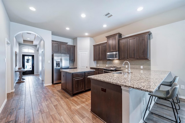211 Clementine Ct, Montgomery, TX 77316 - kitchen with appliances with stainless steel finishes, a sink, dark brown cabinetry, tasteful backsplash, and a peninsula