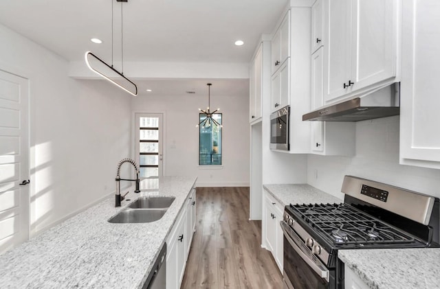 5609 Savyon Dr, Houston, TX 77091 - kitchen with stainless steel appliances, under cabinet range hood, a sink, white cabinets, and backsplash