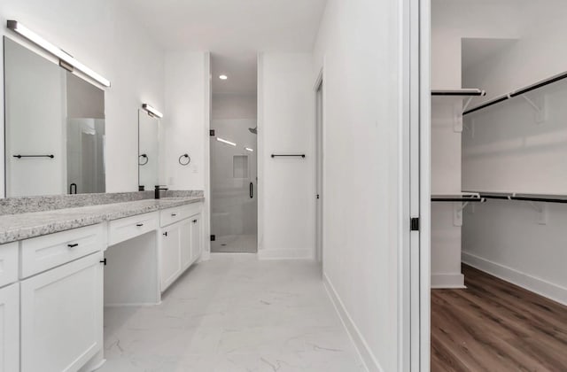 5609 Savyon Dr, Houston, TX 77091 - bathroom featuring a stall shower, a walk in closet, vanity, baseboards, and recessed lighting