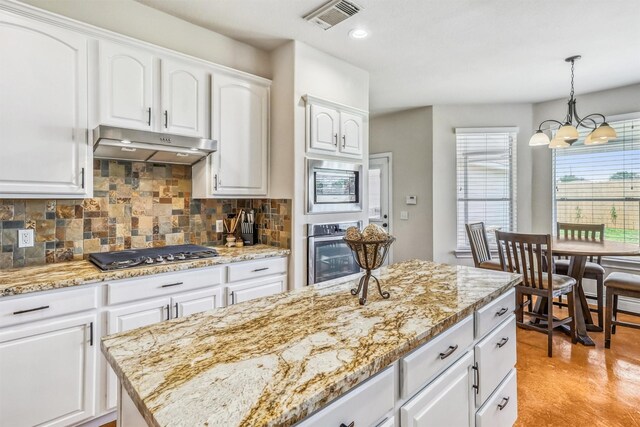 6207 Presidio Canyon Dr, Katy, TX 77450 - kitchen featuring under cabinet range hood, appliances with stainless steel finishes, backsplash, white cabinets, and pendant lighting