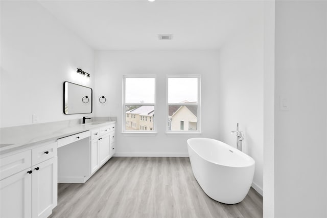 111 Capetown Way, Conroe, TX 77356 - bathroom featuring double vanity, wood finished floors, a freestanding bath, and baseboards