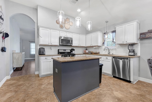 2201 Piney Wood Dr, Deer Park, TX 77536 - kitchen with stainless steel appliances, backsplash, baseboards, arched walkways, and white cabinets