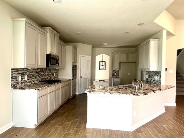 4923 Lacebark Pine Trl, Rosenberg, TX 77471 - kitchen with wall oven, stainless steel microwave, a peninsula, arched walkways, and stone countertops