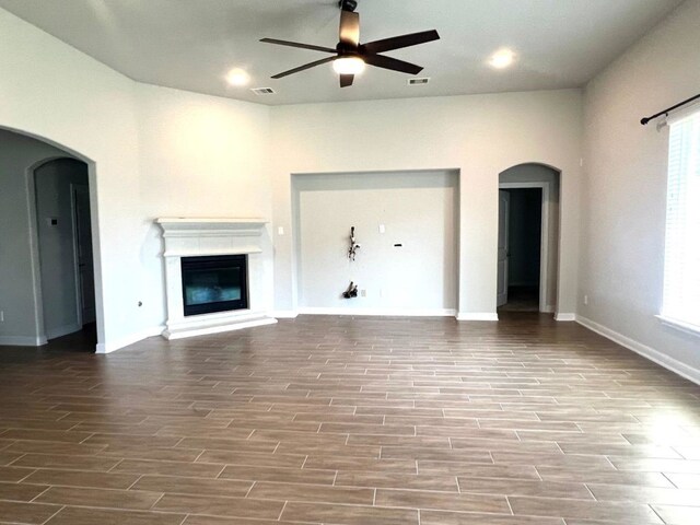 4923 Lacebark Pine Trl, Rosenberg, TX 77471 - unfurnished living room featuring a ceiling fan, arched walkways, wood finished floors, and baseboards