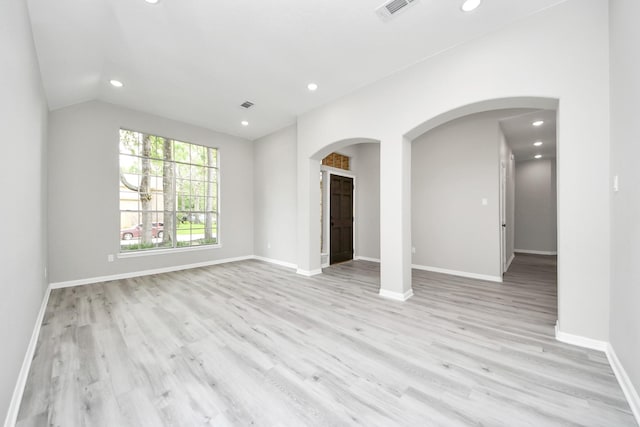 unfurnished living room featuring recessed lighting, light wood-type flooring, arched walkways, vaulted ceiling, and baseboards