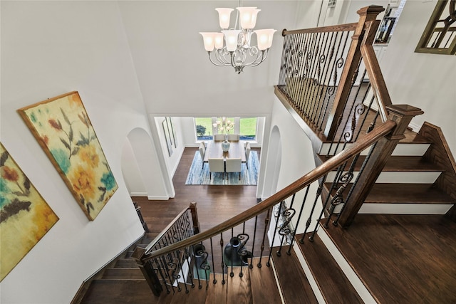 5518 Fleming Rock Ln, Fulshear, TX 77441 - staircase featuring a high ceiling, wood finished floors, a chandelier, arched walkways, and baseboards