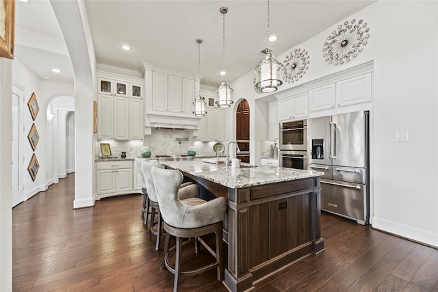 5518 Fleming Rock Ln, Fulshear, TX 77441 - kitchen with appliances with stainless steel finishes, arched walkways, white cabinets, dark wood-style flooring, and recessed lighting