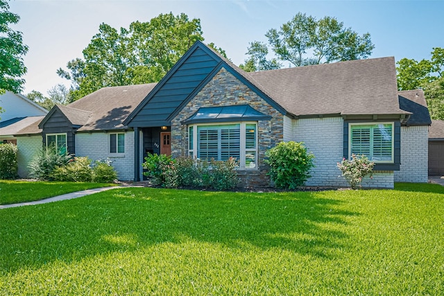 view of front facade featuring a front yard, roof with shingles, brick siding, and a garage