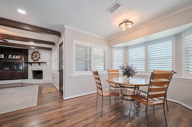 dining room featuring baseboards, wood finished floors, a brick fireplace, and crown molding