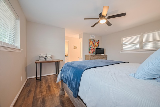 bedroom featuring wood finished floors, ceiling fan, baseboards, and ensuite bath