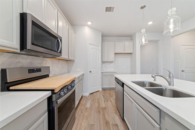 19806 Lone Paddock Cir, Tomball, TX 77377 - kitchen featuring appliances with stainless steel finishes, a sink, light wood-type flooring, light countertops, and decorative backsplash