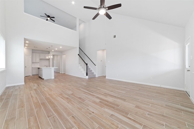 19806 Lone Paddock Cir, Tomball, TX 77377 - unfurnished living room featuring stairs, high vaulted ceiling, a ceiling fan, baseboards, and light wood-type flooring