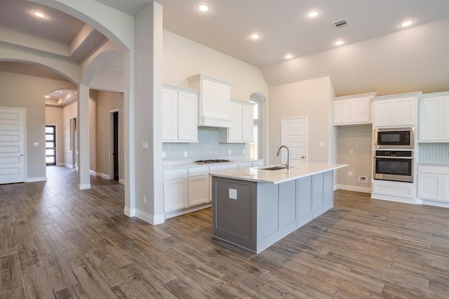1639 Rosedale Dr, Missouri City, TX 77459 - kitchen with appliances with stainless steel finishes, a sink, arched walkways, tasteful backsplash, and white cabinets