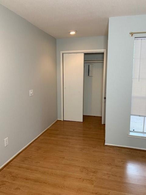 unfurnished bedroom with light wood-style flooring, a closet, and baseboards