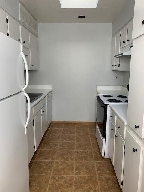 kitchen featuring white appliances, under cabinet range hood, light countertops, and white cabinets