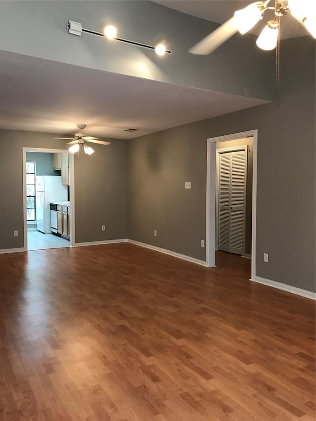 spare room with a ceiling fan, wood finished floors, baseboards, and vaulted ceiling