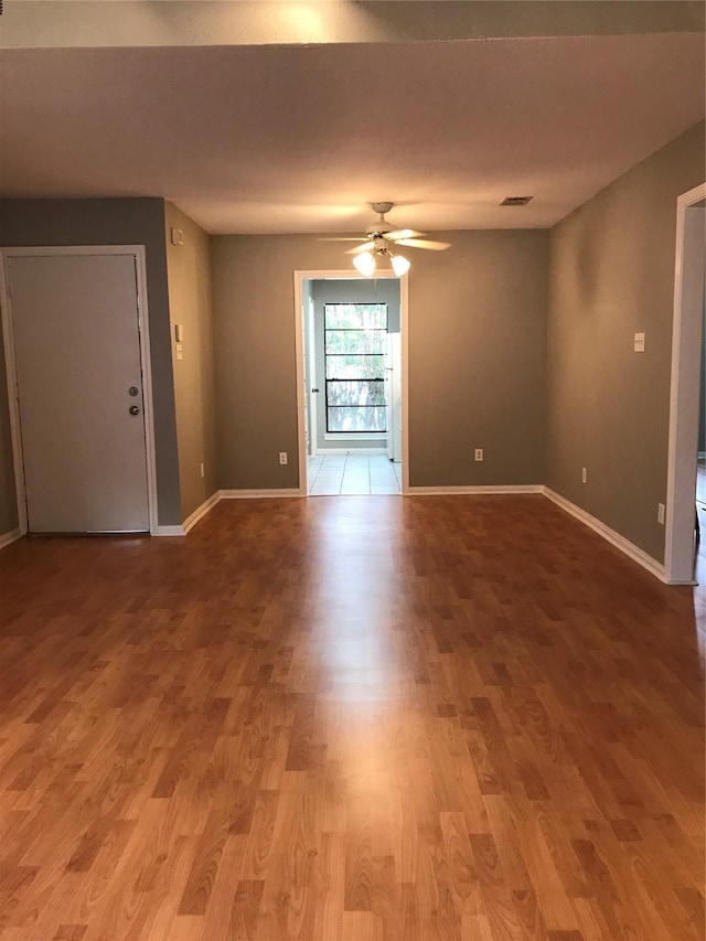 unfurnished room featuring a ceiling fan, wood finished floors, and baseboards