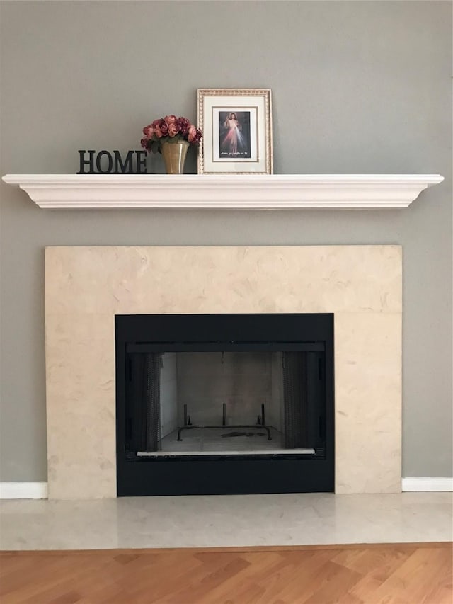 detailed view of a premium fireplace, wood finished floors, and baseboards