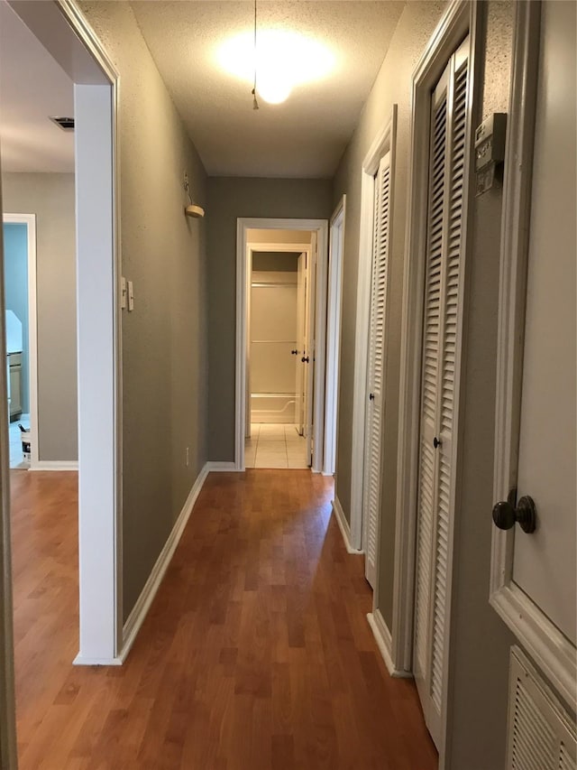 corridor with wood finished floors and baseboards
