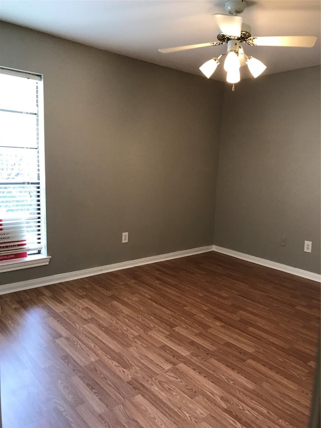 spare room with dark wood-style flooring, baseboards, and ceiling fan