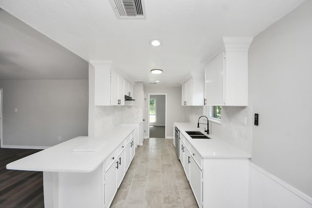 kitchen featuring a sink, light countertops, backsplash, a peninsula, and recessed lighting
