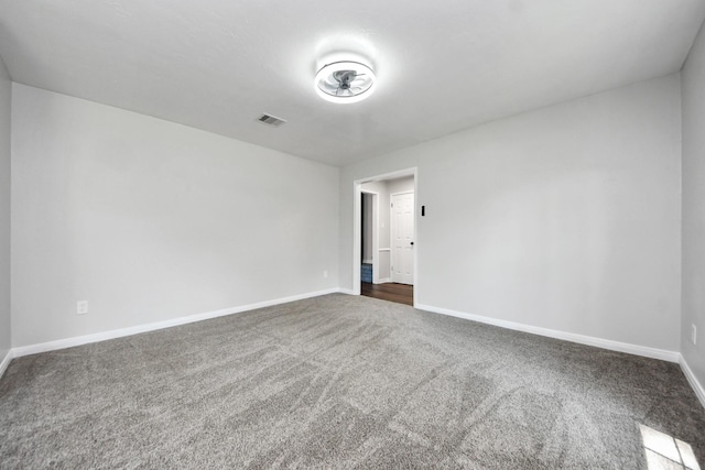 empty room featuring dark colored carpet and baseboards