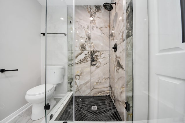 bathroom featuring toilet, a marble finish shower, and baseboards