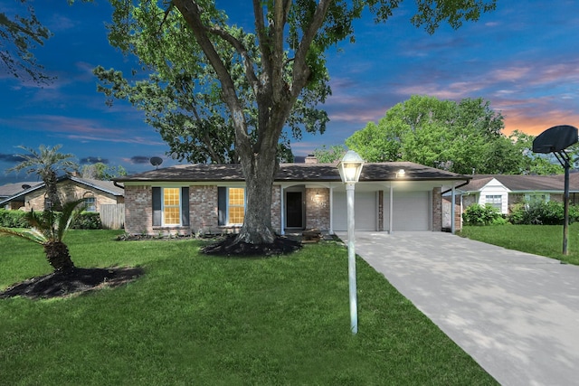 ranch-style house with a garage, a yard, brick siding, and concrete driveway