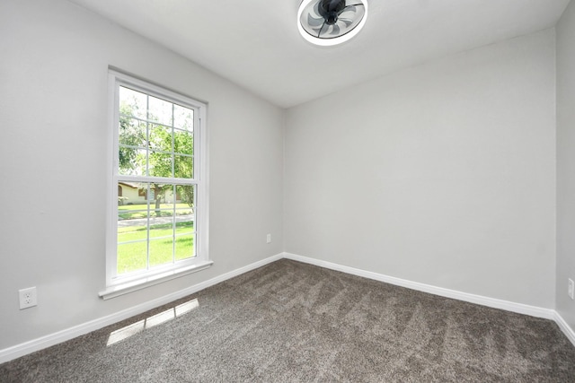 unfurnished room with dark carpet, healthy amount of natural light, and baseboards