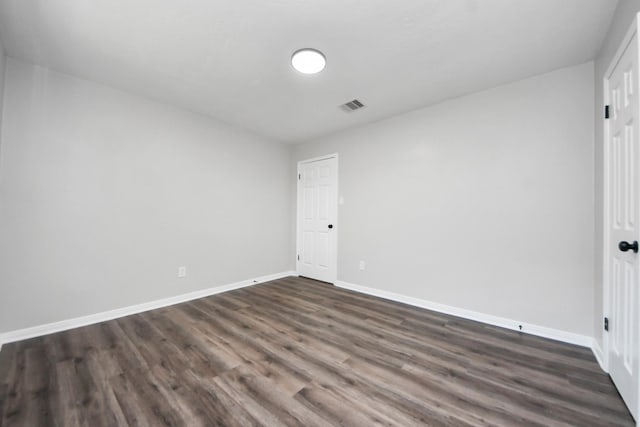 spare room featuring dark wood-style floors and baseboards