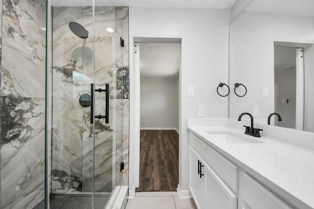 full bathroom with a marble finish shower, vanity, baseboards, and tile patterned flooring