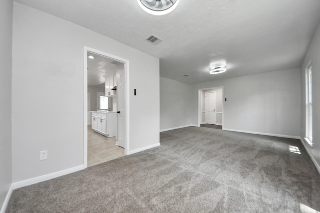 unfurnished room featuring carpet flooring, baseboards, and a textured ceiling