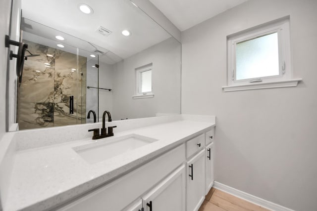 bathroom featuring vanity, baseboards, a marble finish shower, recessed lighting, and wood finished floors