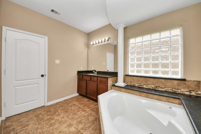 full bath with plenty of natural light, a garden tub, vanity, and baseboards