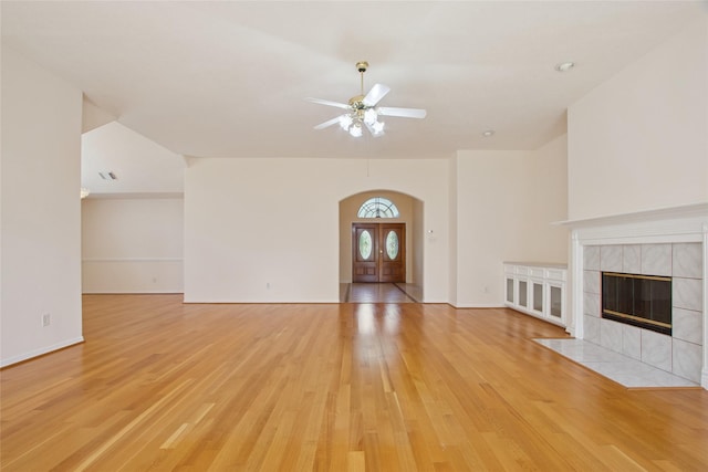 18415 Deer Crossing Dr, Humble, TX 77346 - unfurnished living room featuring arched walkways, light wood finished floors, a fireplace, ceiling fan, and french doors