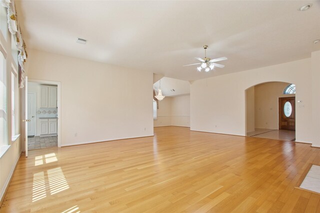 18415 Deer Crossing Dr, Humble, TX 77346 - unfurnished living room featuring arched walkways, a ceiling fan, and light wood-style floors