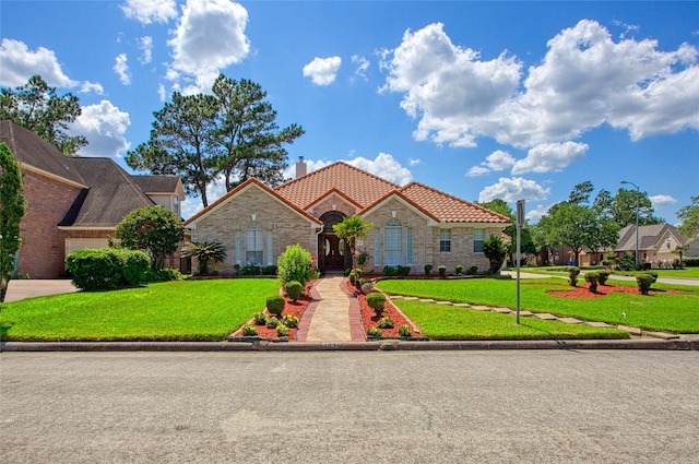 18415 Deer Crossing Dr, Humble, TX 77346 - view of front facade featuring a tiled roof, a front yard, stone siding, and a chimney