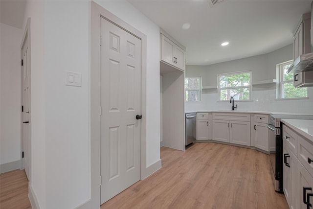23331 Balthasar St, Spring, TX 77373 - kitchen with stainless steel appliances, open shelves, a sink, decorative backsplash, and light wood-style flooring