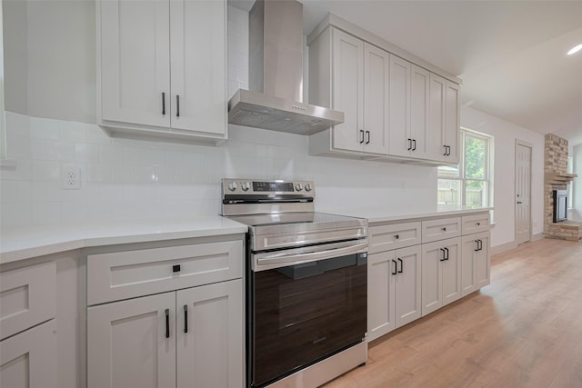 23331 Balthasar St, Spring, TX 77373 - kitchen with wall chimney exhaust hood, electric stove, light wood-type flooring, and decorative backsplash