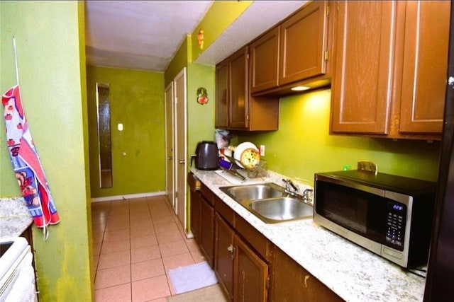 12506 Autumn Leaf Ln, Houston, TX 77072 - kitchen with stainless steel microwave, a sink, light tile patterned floors, light countertops, and brown cabinets