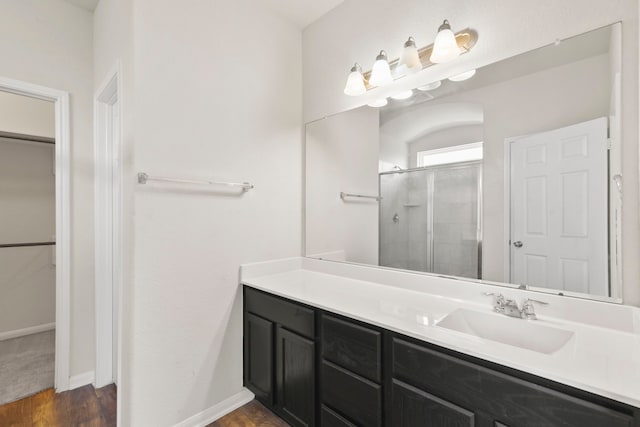 3011 Tandem Ct, Rosenberg, TX 77471 - bathroom with a shower stall, vanity, wood finished floors, a walk in closet, and baseboards