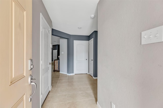 hallway featuring light tile patterned flooring and baseboards