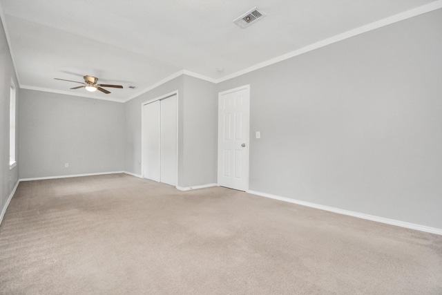 empty room with ornamental molding, ceiling fan, light carpet, and baseboards