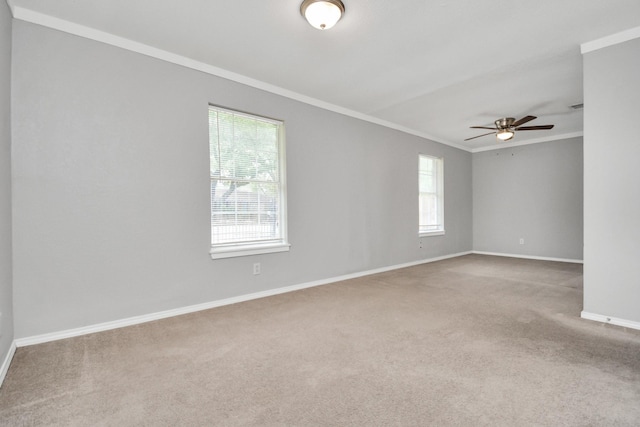 carpeted empty room featuring plenty of natural light, ornamental molding, a ceiling fan, and baseboards
