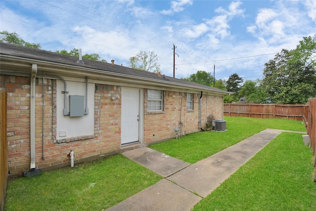 view of exterior entry featuring central air condition unit, brick siding, and a shingled roof