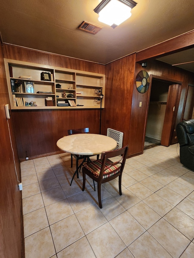 dining space with wood walls and light tile patterned floors