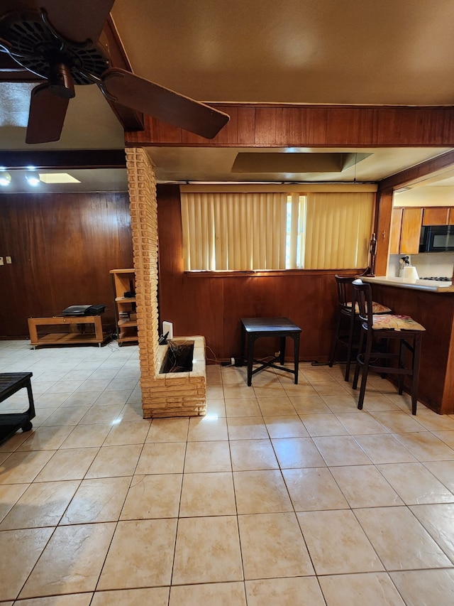 tiled living area with wooden walls and ceiling fan